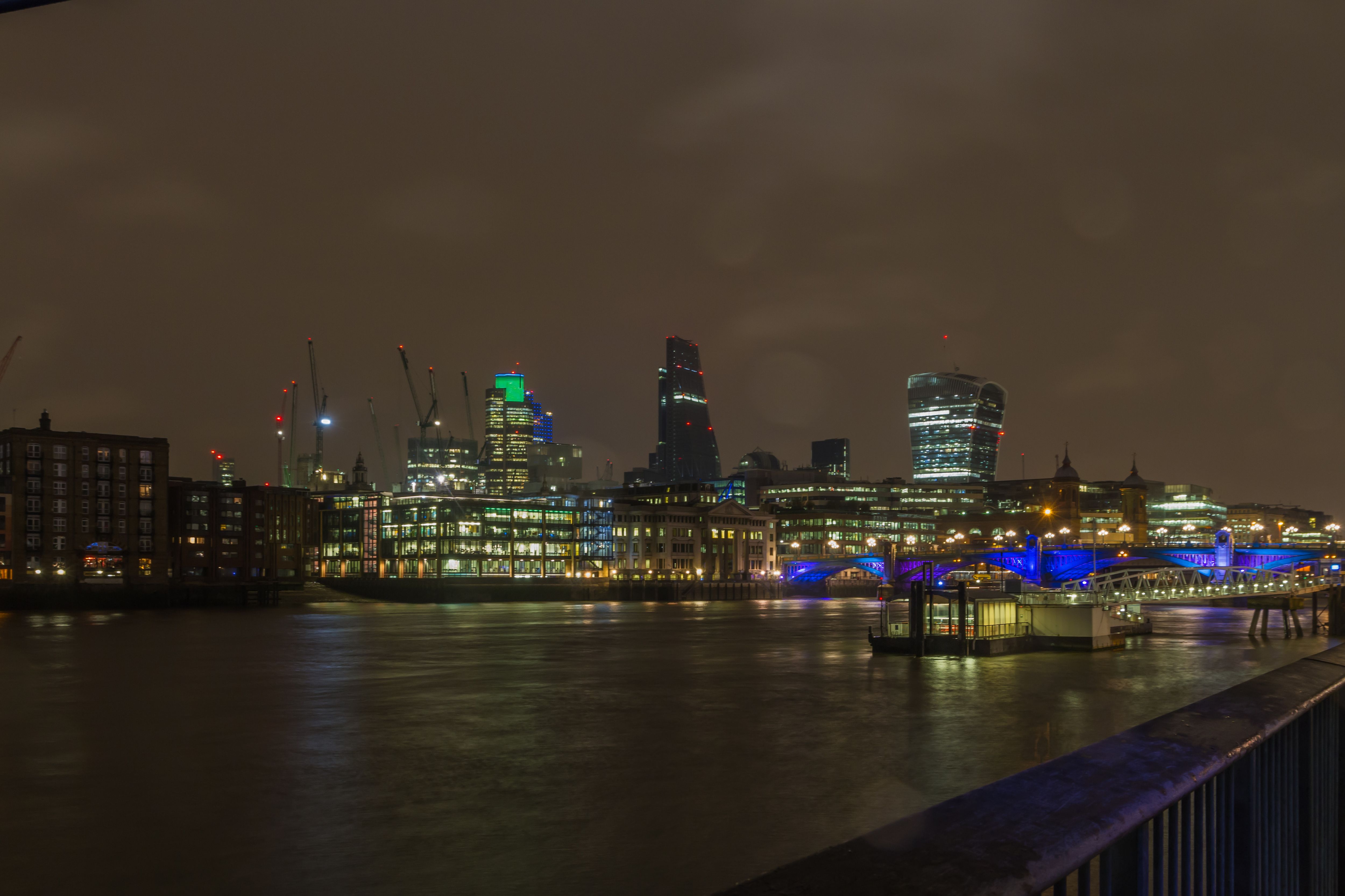 The City of London skyline at night, seen across the Thames near Southwark Bridge